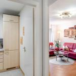 Wohnzimmer mit rotem Sofa und Küchenbereich mit Schränken