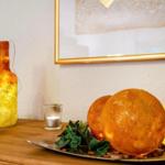 Holztisch mit dekorativen Kugeln, Kerzen und einer beleuchteten Flasche.