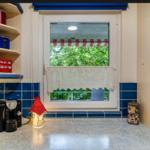 Küche mit Fenster, blauen Fliesen und Küchenutensilien.