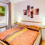 Schlafzimmer mit Bett, zwei Nachttischen und Fenster mit Blick auf Grün.