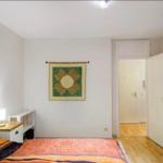 Schlafzimmer mit Bett, Nachttisch, Wandbild und Kleiderschrank.