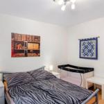 Schlafzimmer mit Bett, Wickelkommode und Wandbildern.