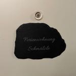 Schwarzer Stein mit Aufschrift Ferienwohnung Schmälzle und Duschkopf darüber