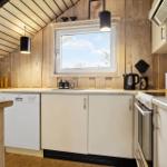 Küche mit Holzwand, Fenster, Spüle, Kühlschrank und Kochfeld.