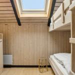 Zimmer mit Holzwand, Doppelstockbett und Dachfenster.