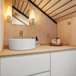 Badezimmer mit Waschbecken, Spiegel und Holzwand