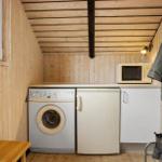 Kleine Küche mit Waschmaschine, Spülmaschine und Mikrowelle. Holzwände und -decke.
