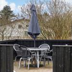 Terrasse mit Tisch, Stühlen und geschlossenem Sonnenschirm.