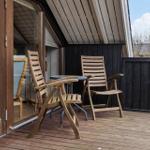 Terrasse mit zwei Holzstühlen und Tisch vor einem Haus mit Glasfront.