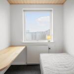 Ein Schlafzimmer mit Bett, Schreibtisch und Fenster.