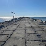 Steinpflasterweg führt über das Wasser zu einem Leuchtturm.