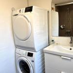 Waschmaschine und Trockner stehen im Bad. Spiegel und Waschbecken sind vorhanden.