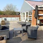 Terrasse mit Sitzgruppe, Sonnenliegen und Grillplatz an Hauswand.