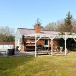 Haus mit Terrasse, Grillbereich und Garten. Weiße Veranda mit Tisch und Stühlen.