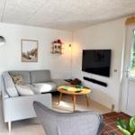 Wohnzimmer mit Sofa, Fernseher und Tisch. Durchgang zur Schlafzimmer.