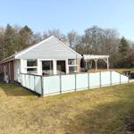 Haus mit Terrasse und Garten. Holzveranda und Glasgeländer sichtbar.