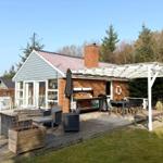 Haus mit Terrasse, Grill und Sitzgelegenheiten im Freien.