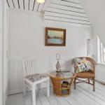 Room with white walls, wooden floor, and sloped ceiling beams. A round table and two chairs are in the room.