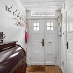 Entrance with white door, coat hooks, and wooden cabinet.