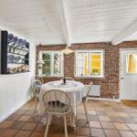 Dining room with table, chairs, brick wall, and terracotta floor.