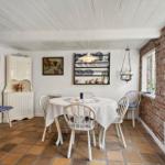 Dining room with round table, white chairs, and brick wall