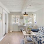 A living room with blue and white sofa, wooden floor and white walls. A picture hangs on the wall.