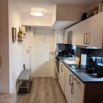 Kitchen with worktop, sink, and cabinets. Hallway with bench and door.