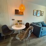 Dining area with round table, chairs, and sofa. Pendant lamp and wall art.