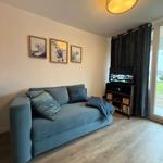 Living room with sofa, TV, and wooden floor.