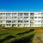 Modern apartment building with balconies and lawn in front.