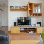 Wohnzimmer mit Fernseher, Holzmöbel und Bücherregal.