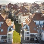 Meerfront-Apartments mit roten Dächern und Balkonen.