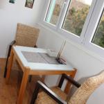 Essbereich mit Tisch und zwei Stühlen, großes Fenster mit Blick auf Grünflächen.