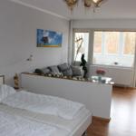 Schlafzimmer mit Bett und Sitzbereich. Fenster mit Blick nach draußen.