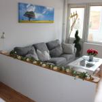Wohnbereich mit grauem Sofa, weißen Möbeln und Fensterblick.