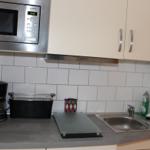 Küche mit Mikrowelle, Kaffeemaschine, Toaster und Spüle.