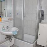 Badezimmer mit Dusche, Waschbecken und Spiegel