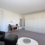 Wohnbereich mit Ledersofa, Esstisch und großen Schränken.