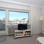 Wohnzimmer mit TV, Bücherregal und Balkonansicht