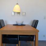 Esszimmer mit Holztisch, zwei schwarzen Stühlen und einer Deckenlampe.