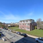 Rotes Backsteingebäude mit Dachfenstern und Grünfläche