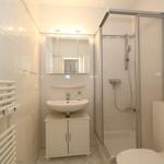 Badezimmer mit Dusche, Waschbecken und Heizung.