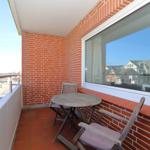 Terrasse mit Tisch und Stühlen, rote Ziegelwand und Fensterblick.
