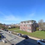 Rotes Backsteinhaus mit Dachgauben und umliegenden Grünflächen.