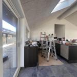 Raum mit Dachfenster, Leitern und Werkzeug auf dunklem Boden und hellen Wänden.
