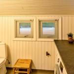 Badezimmer mit Toilette, Waschbecken und zwei Fenstern.