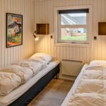 Zwei Einzelbetten in einem Raum mit Holzwänden und Fenster.