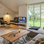 Wohnzimmer mit Kamin, TV und großem Fenster. Holzboden und Sofa.
