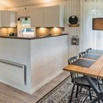 Küche mit Essbereich, Holztisch, schwarze Stühle und Kücheninsel.