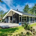 Moderne Holzhütte mit Terrasse, Grill und Garten. Umgeben von Bäumen und Gras.